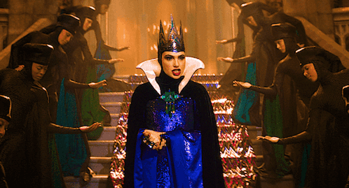 A Woman With A Crown On Her Head Stands In Front Of A Group Of People GIF