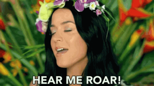 A Woman With A Flower Crown On Her Head Is Screaming And Saying `` Hear Me Roar '' . GIF