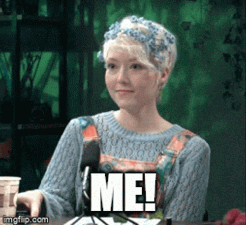 A Woman With A Flower Crown On Her Head Is Sitting In Front Of A Microphone And Says Me GIF