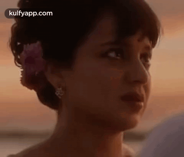 A Woman With A Flower In Her Hair Is Looking At A Man . GIF