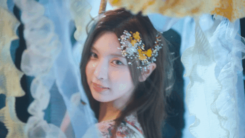 Woman With Flower In Hair Standing In Front Of Curtain GIF