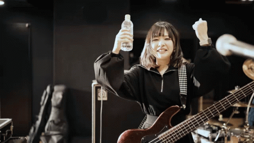 A Woman With A Guitar Is Holding A Bottle Of Water GIF