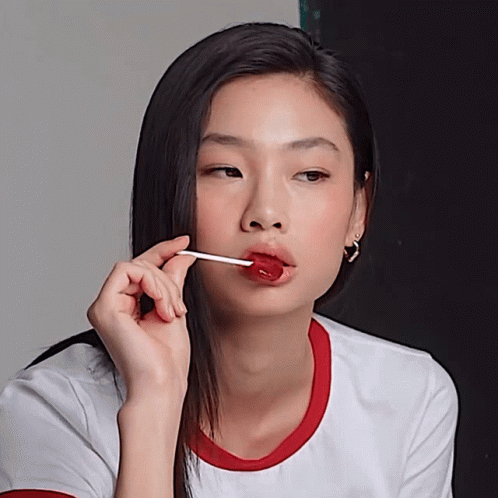 A Woman With A Lollipop In Her Mouth Looks At The Camera GIF