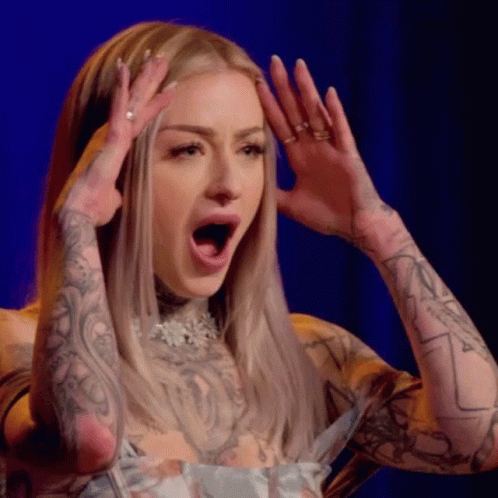 A Woman With A Lot Of Tattoos On Her Arms Is Making A Surprised Face With Her Mouth Open . GIF