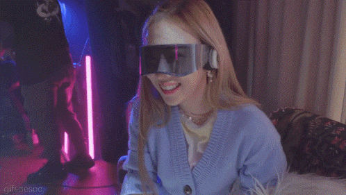 a woman with a mask on her face is wearing a blue cardigan and goggles