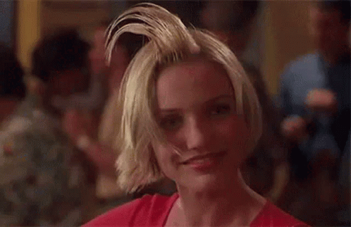 A Woman With A Mohawk Is Smiling And Looking At The Camera In A Crowded Room . GIF