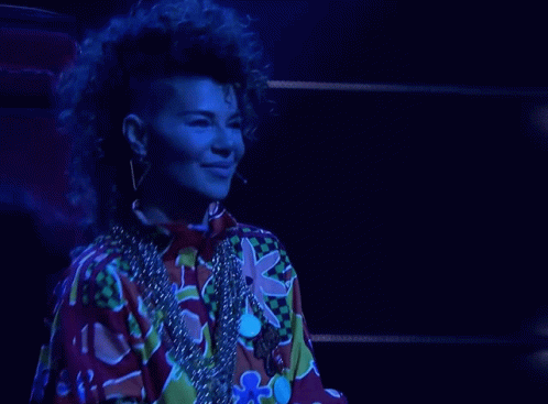 A Woman With A Mohawk Is Wearing A Colorful Shirt And A Necklace GIF