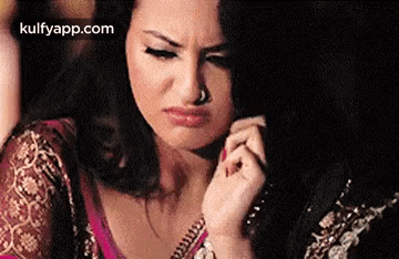 A Woman With A Nose Ring Is Making A Funny Face While Holding Her Hair . GIF