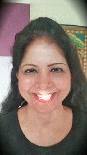A Woman With A Nose Ring Is Smiling With A Light Coming Out Of Her Mouth GIF
