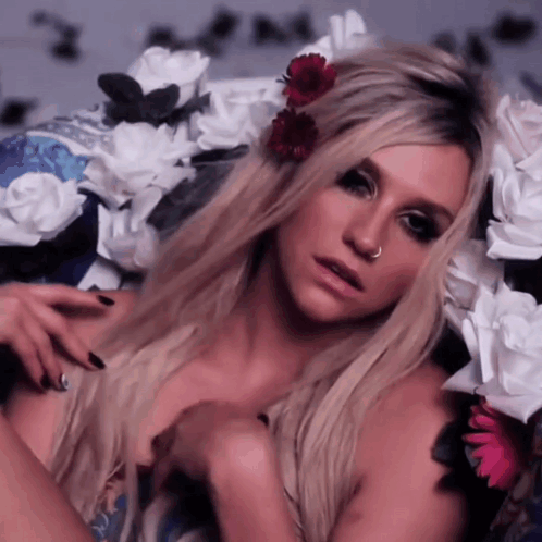 A Woman With A Nose Ring Is Surrounded By Flowers GIF