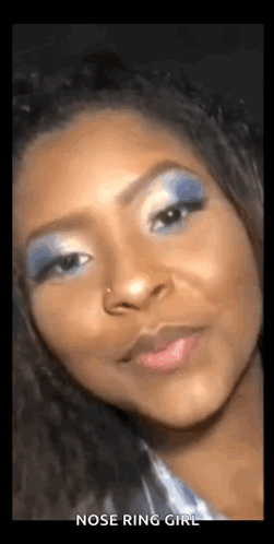 A Woman With A Nose Ring Is Wearing Blue Eye Shadow . GIF