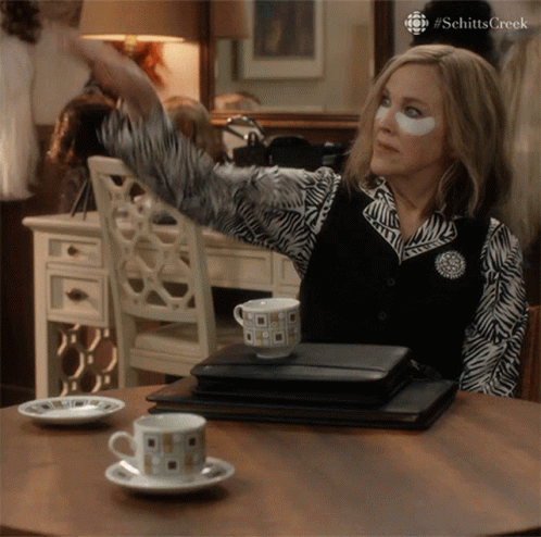 A Woman With A Patch On Her Eye Is Sitting At A Table With A Cup Of Coffee On It GIF