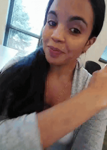 A Woman With A Piercing In Her Nose Is Smiling And Looking At The Camera GIF