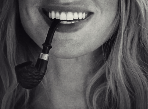A Woman With A Pipe In Her Mouth And A Smile On Her Face GIF
