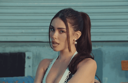 A Woman With A Ponytail And Pearl Earrings Looks To The Side GIF