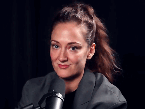 A Woman With A Ponytail Is Standing In Front Of A Microphone GIF