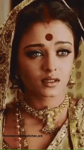 A Woman With A Red Dot On Her Forehead Is Wearing A Gold Necklace GIF