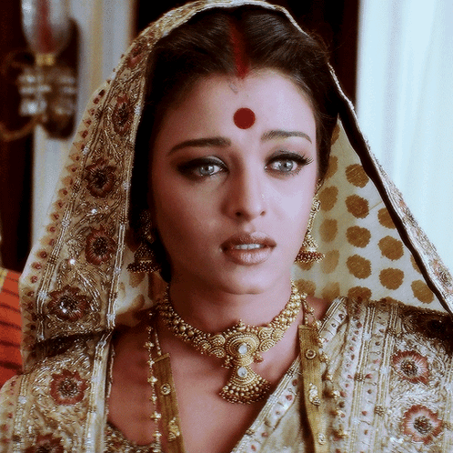 A Woman With A Red Dot On Her Forehead Is Wearing Gold Jewelry GIF