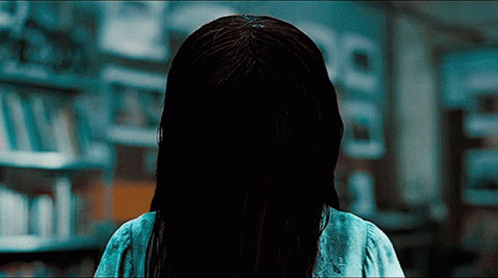 A Woman With A Ring In Her Hair Is Standing In A Library GIF