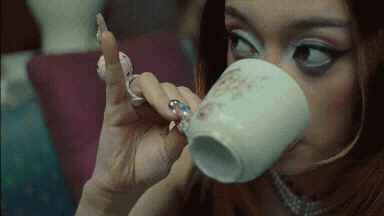 A Woman With A Ring On Her Finger Drinks From A Cup GIF