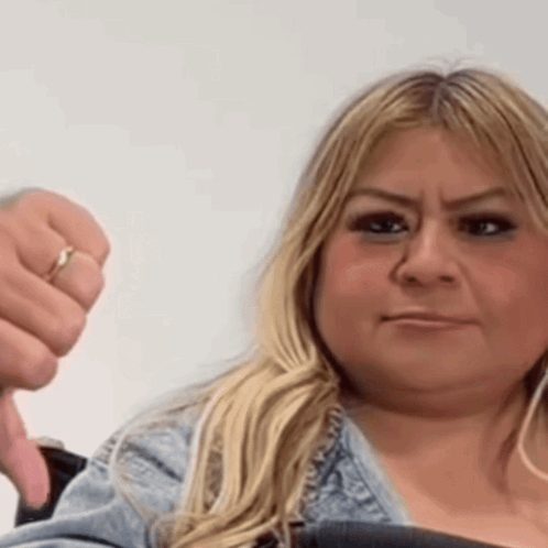 a woman with a ring on her finger is giving a thumbs down