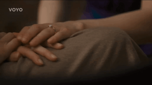 A Woman With A Ring On Her Finger Is Holding A Man 'S Hand With The Word Voyo On The Bottom GIF