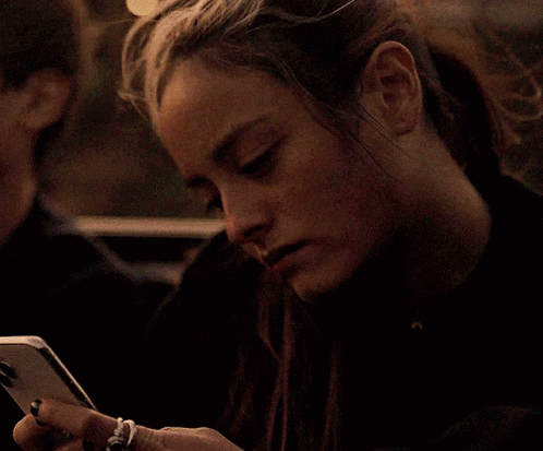 A Woman With A Ring On Her Finger Is Looking At Her Cell Phone GIF