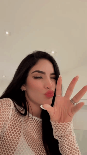 A Woman With A Ring On Her Finger Is Making A Kissing Face GIF