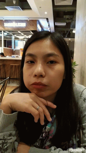 a woman with a ring on her finger is sitting in front of a sandwich shop