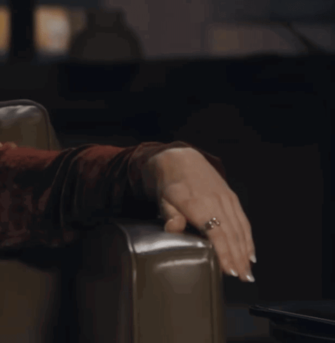 A Woman With A Ring On Her Finger Is Sitting On A Chair GIF