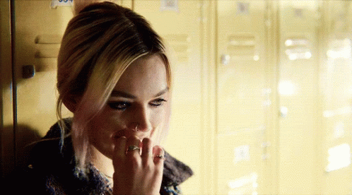 A Woman With A Ring On Her Finger Is Standing In Front Of A Row Of Lockers GIF