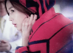 A Woman With A Ring On Her Finger Is Wearing A Red And Blue Sweater GIF