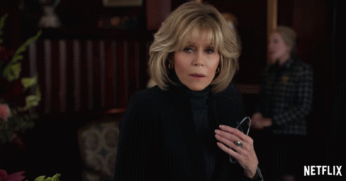 A Woman With A Ring On Her Finger Stands In Front Of A Netflix Ad GIF