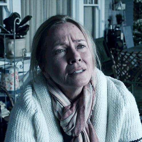 A Woman With A Scarf Around Her Neck And A White Sweater GIF