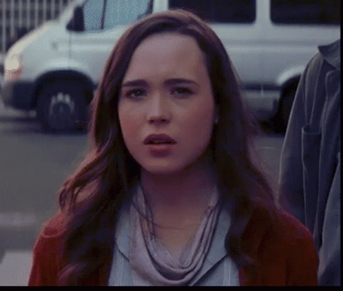 A Woman With A Scarf Around Her Neck Is Looking At The Camera GIF