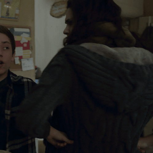 A Woman With A Scarf Around Her Neck Stands Next To Another Woman In A Kitchen GIF