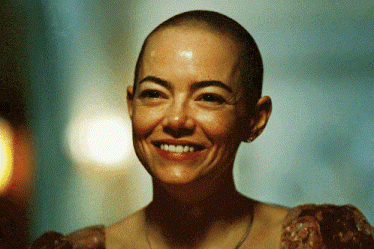 a woman with a shaved head is smiling in a blurry photo
