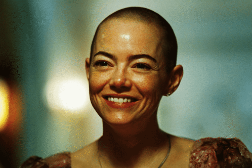 a woman with a shaved head is smiling