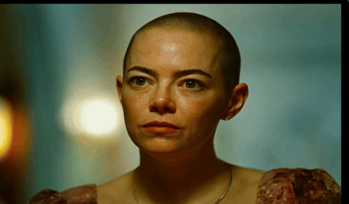 a woman with a shaved head is wearing a dress