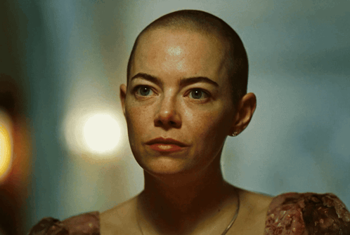 a woman with a shaved head is wearing a dress