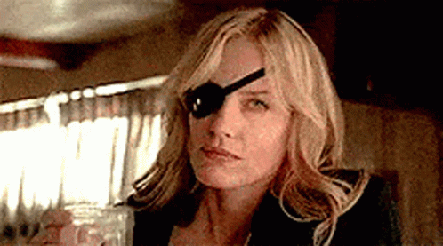 A Woman With A Spoon In Her Eye Is Holding A Glass Of Water . GIF