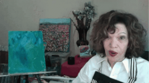 A Woman With A Surprised Look On Her Face Is Holding A Book GIF