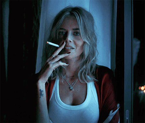 A Woman With A Tattoo Of A Lizard On Her Wrist Smoking A Cigarette GIF