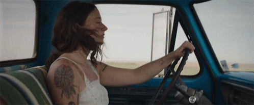 A Woman With A Tattoo On Her Arm Is Driving A Truck GIF