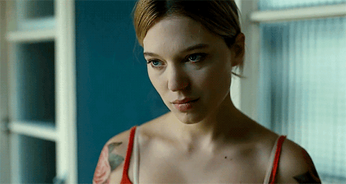 A Woman With A Tattoo On Her Arm Is Looking Out Of A Window GIF
