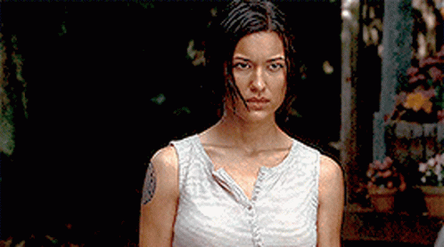 A Woman With A Tattoo On Her Arm Is Standing In A Dark Room GIF
