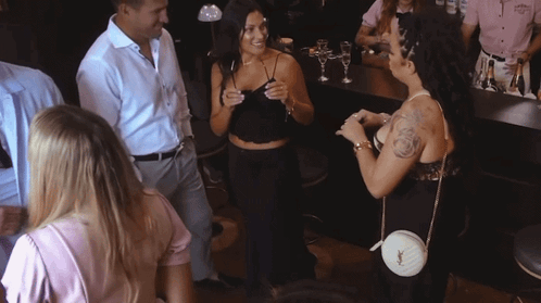 A Woman With A Tattoo On Her Arm Is Talking To A Man In A White Shirt GIF