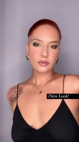 A Woman With A Tattoo On Her Arm Is Wearing A Black Tank Top And A Necklace GIF