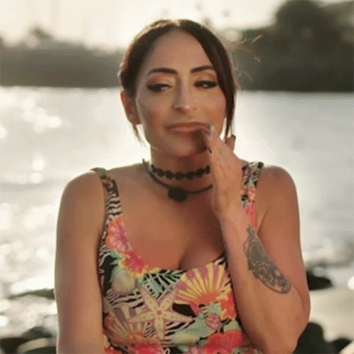 A Woman With A Tattoo On Her Arm Is Wearing A Floral Tank Top GIF