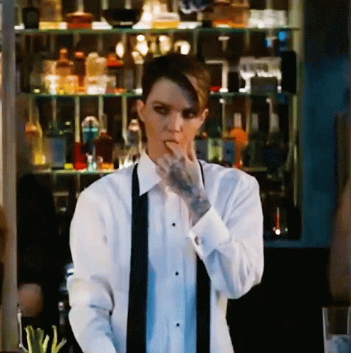 A Woman With A Tattoo On Her Arm Is Wearing A Tuxedo And A Black Tie GIF